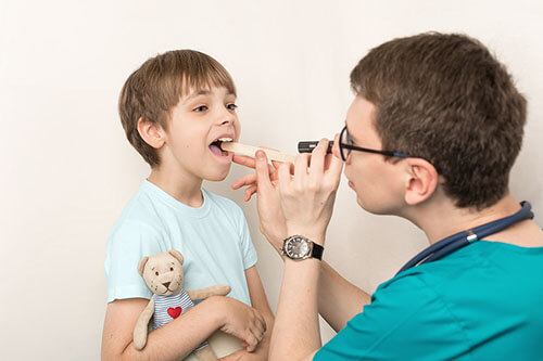 Doctor examines child with strep throat Doctor examines child with strep throat