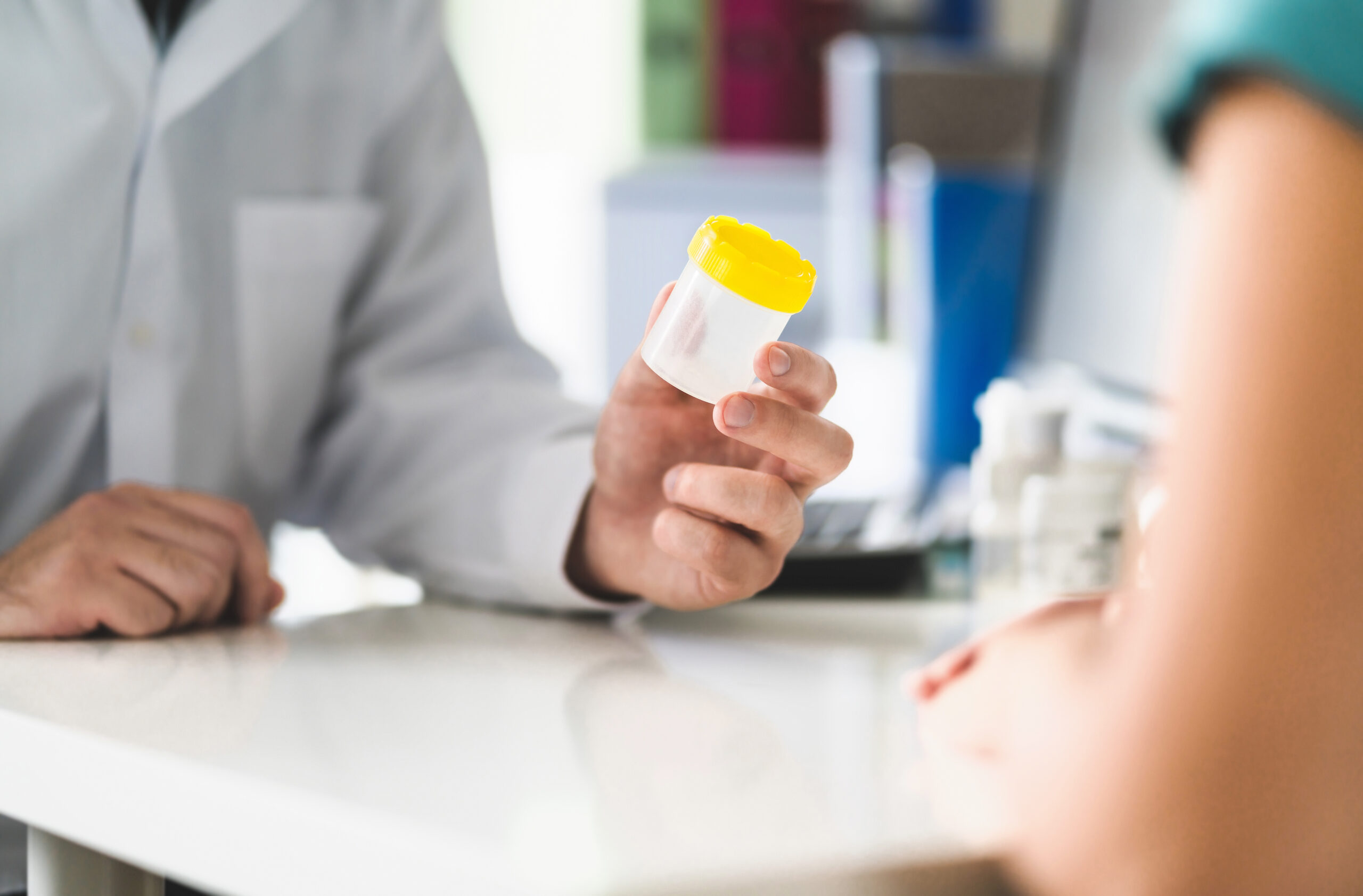 Doctor, patient and urine test cup. Physician giving pee contain STD Test being discussed in an urgent care